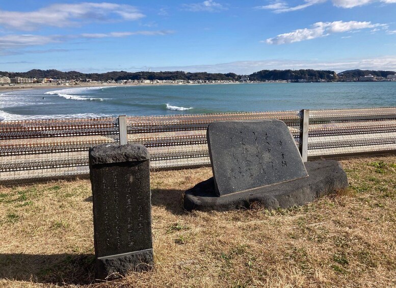 A coastal view with a fence, a stone monument, and a beach in the background. 2