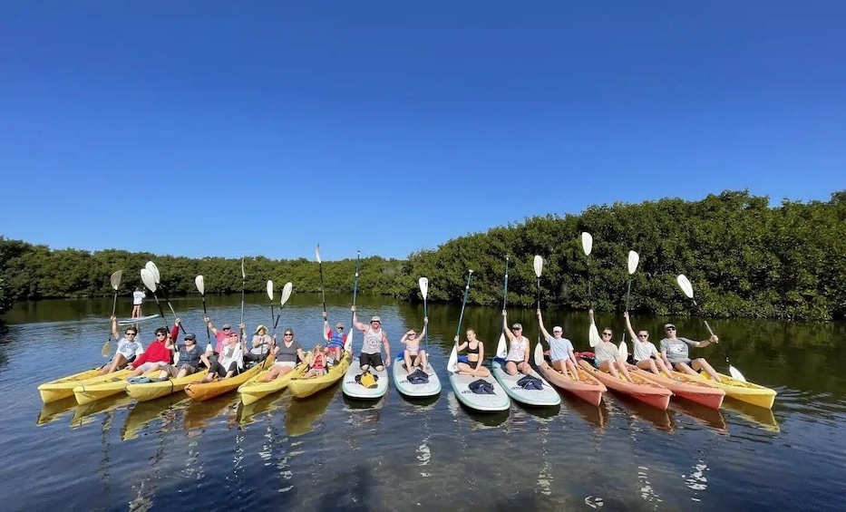 A group of people in kayaks on a calm river, surrounded by lush greenery. 4