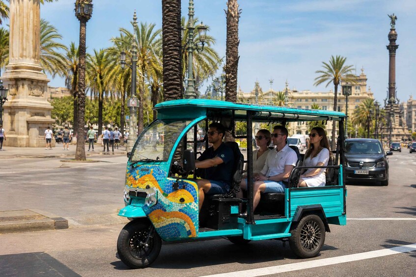 A turquoise tuk-tuk with passengers, palm trees, and historic architecture in the background. 5