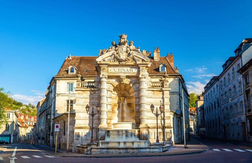 A historic building with ornate architecture and a fountain in front. 3