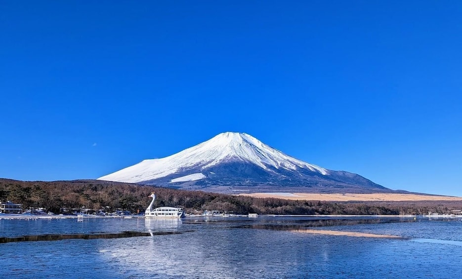 A snow-capped mountain, a body of water, and a boat. 3