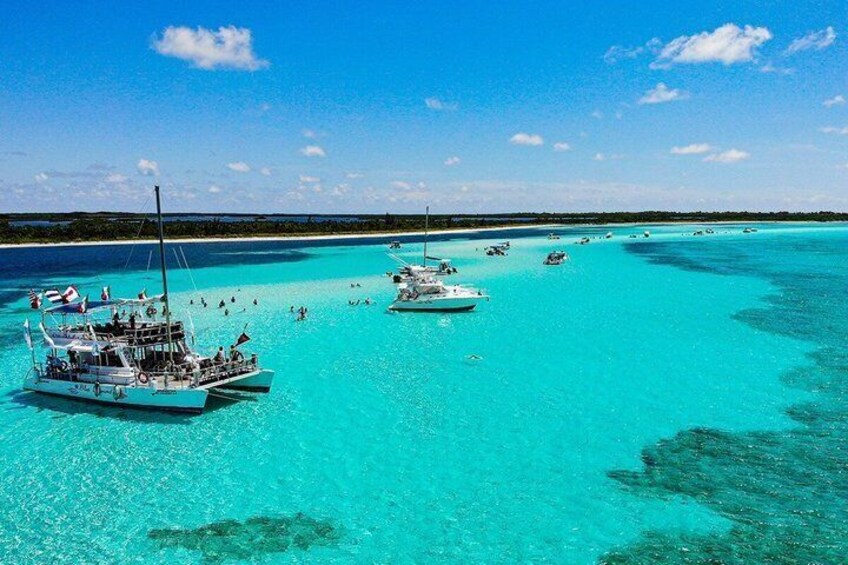 A turquoise sea with boats anchored, clear skies, and a distant shoreline. 3