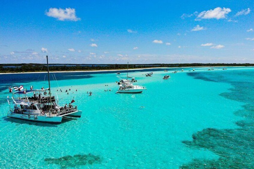 A turquoise sea with boats anchored, clear skies, and a distant shoreline. 2