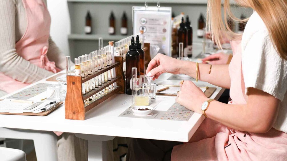 A person pouring a liquid into a small glass, with a wooden rack of bottles and a menu in the background. 2