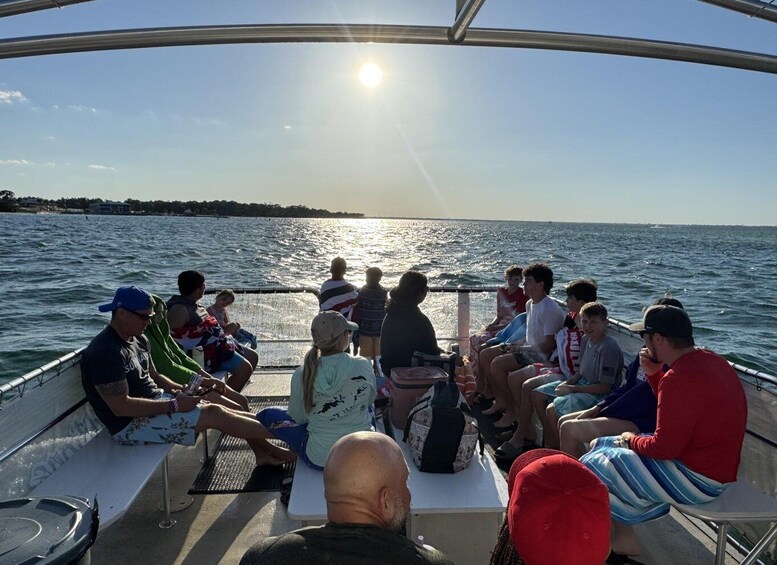 A group of people on a boat with the sun setting over the water. 5