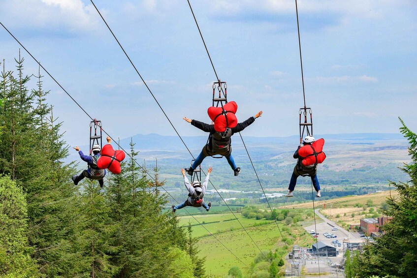 Three people bungee jumping with red parachutes, surrounded by trees and a distant view of a town. 2