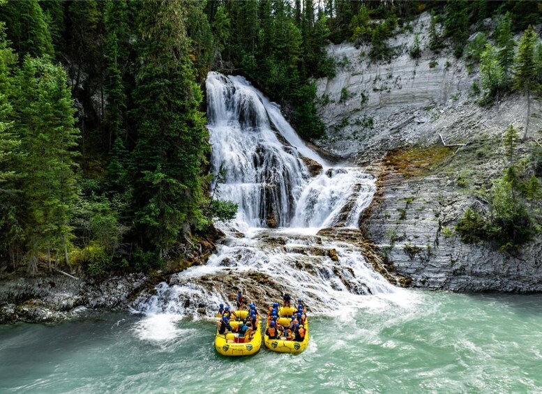 A waterfall, a river, and two yellow inflatable rafts with people. 1