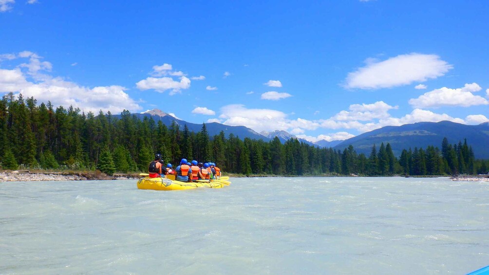 A group of people rafting down a river surrounded by mountains and dense forests. 4