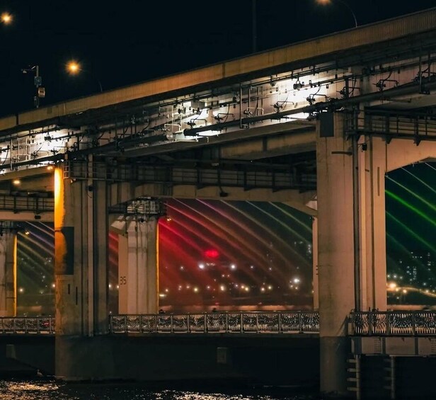 A nighttime view of a bridge with illuminated road markings and structural beams. 1