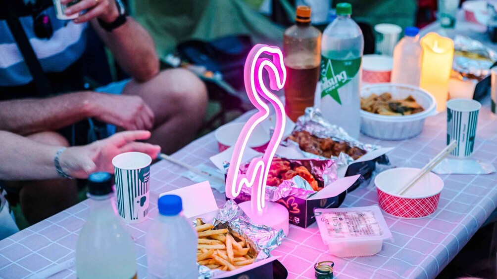 A table with food items, a neon flamingo sign, and a bottle of Mountain Dew. 5