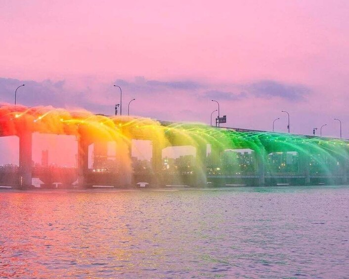A bridge with colorful lights reflecting on the water. 1