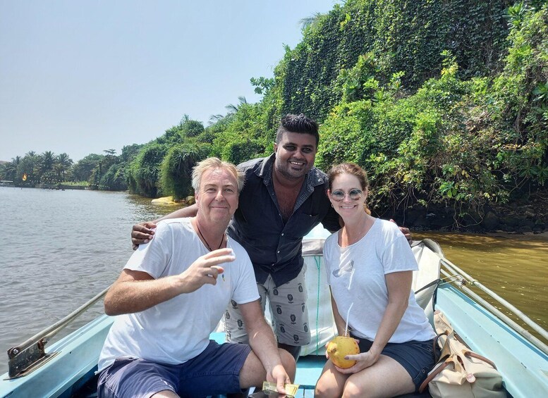Three people on a boat with a river and dense greenery in the background. 2