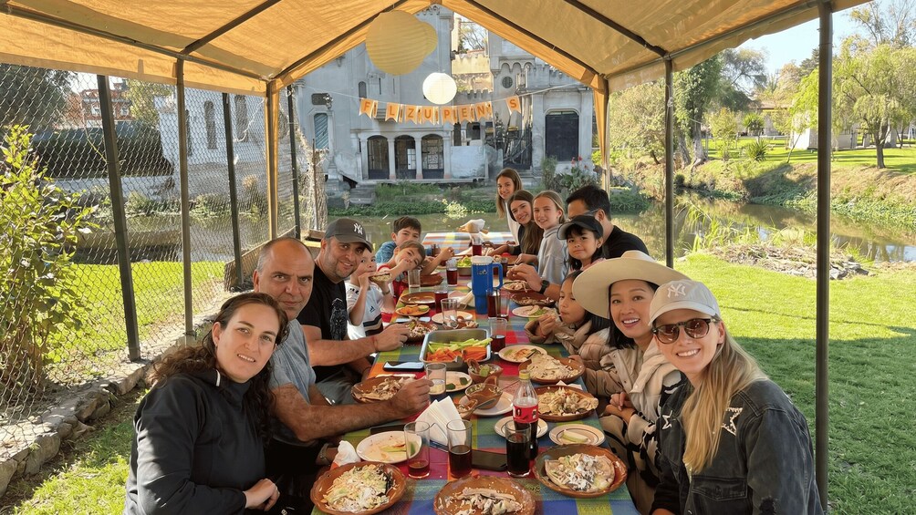 A group of people dining at a table under a tent with a banner reading 'ELIZABO'S' in front of a building. 3