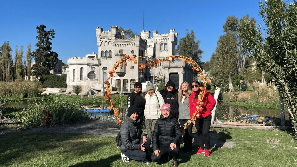 A group of people posing in front of a castle with a decorative archway. 2