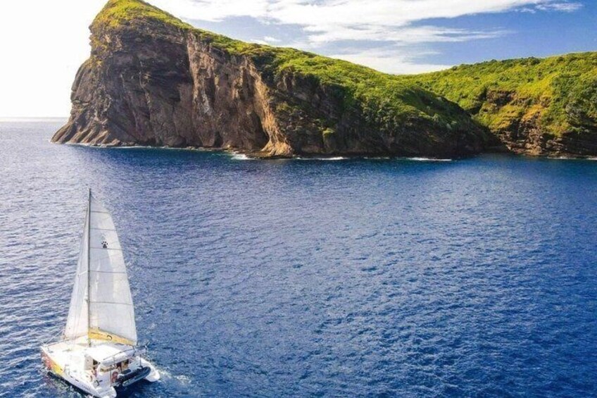 A sailboat on a calm sea with a green island in the background. 4