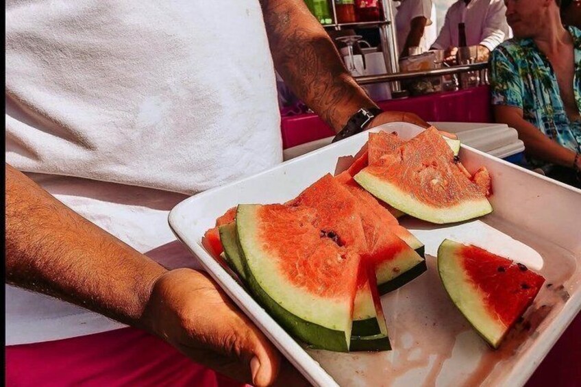 A person holding a tray with watermelon slices. 3
