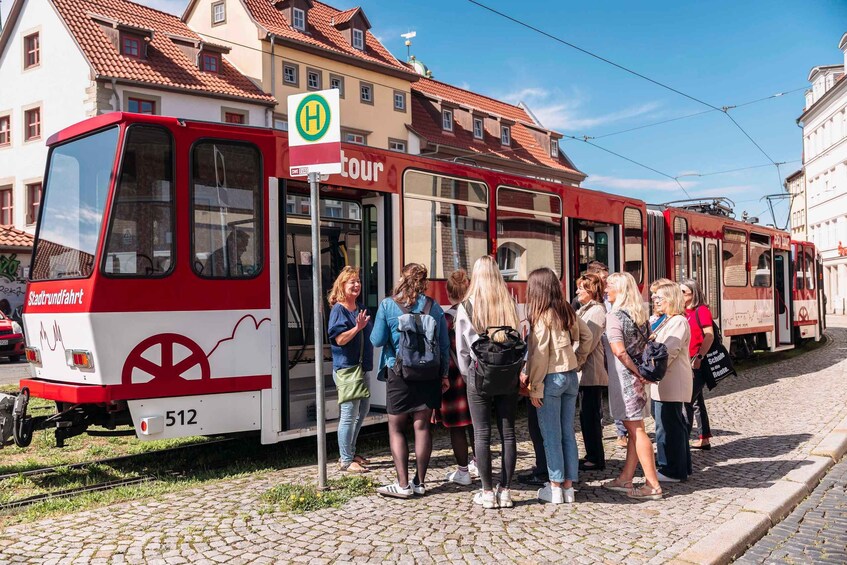A red tram with passengers boarding at a station. 5