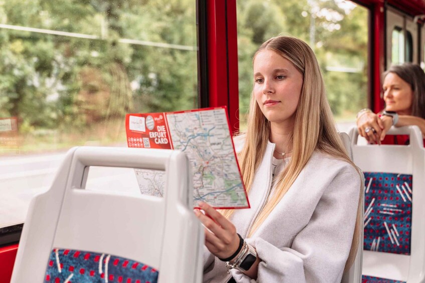 A person holding a map on a bus with a window view of greenery. 3
