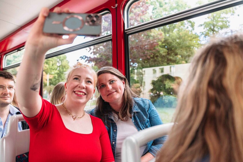 A person taking a selfie with a smartphone inside a vehicle with a red interior. 1