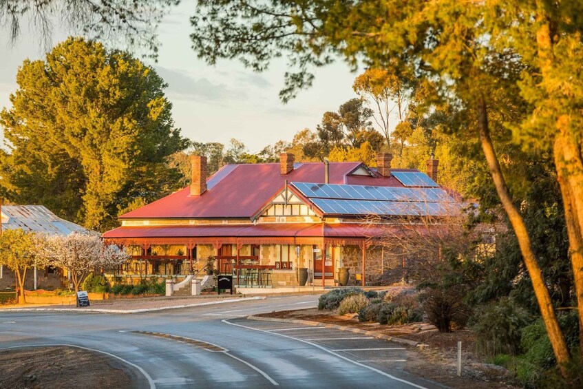 A red-roofed building with solar panels, surrounded by trees and a clear road. 1