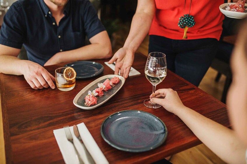 A wooden table with plates, a glass of white wine, and a glass with a slice of orange. 3