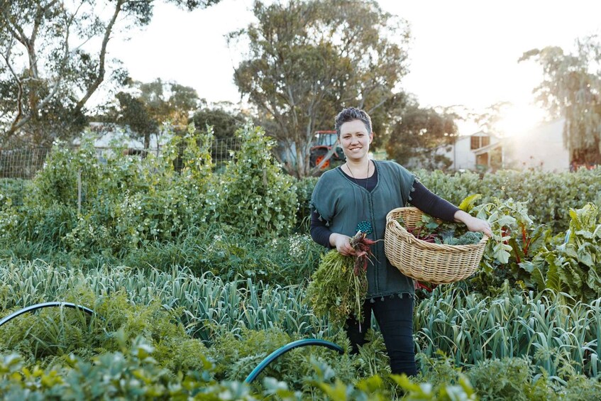A person holding a basket of vegetables in a lush garden. 5
