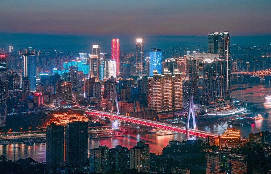 A cityscape at night with illuminated skyscrapers, a prominent red bridge, and a river reflecting city lights. 5