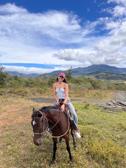 A person riding a horse on a grassy field with mountains in the background. 5