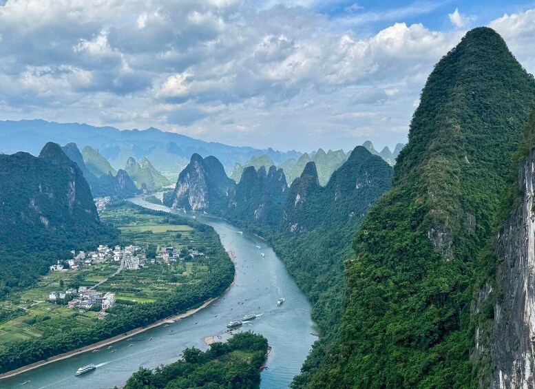 A river winding through a valley with limestone karst formations and a small settlement along the water's edge. 3