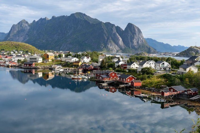 A coastal town with red buildings, a calm lake, and mountains in the background. 4