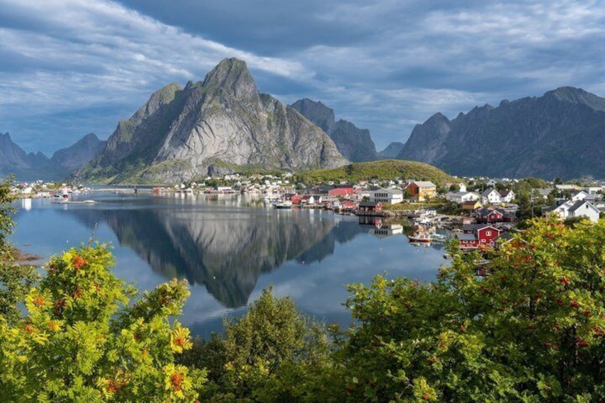 A fjord with a mountain, a small town, and calm water. 5
