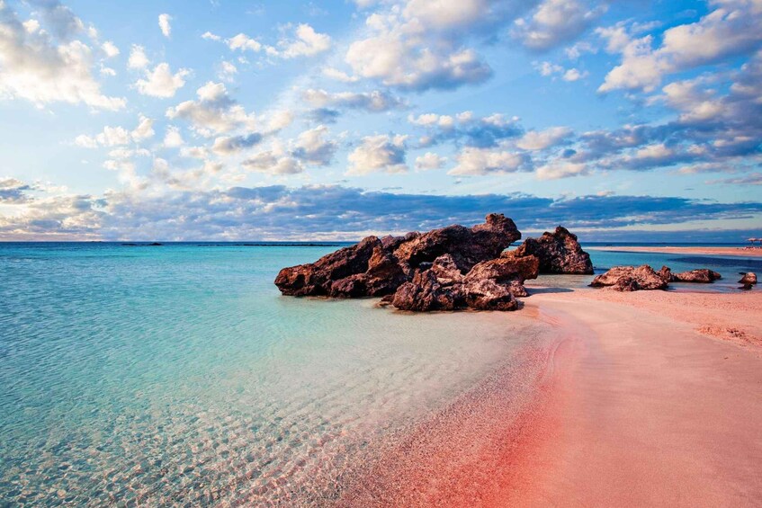 A beach with clear turquoise water, a sandy shore, and large rocks. 5
