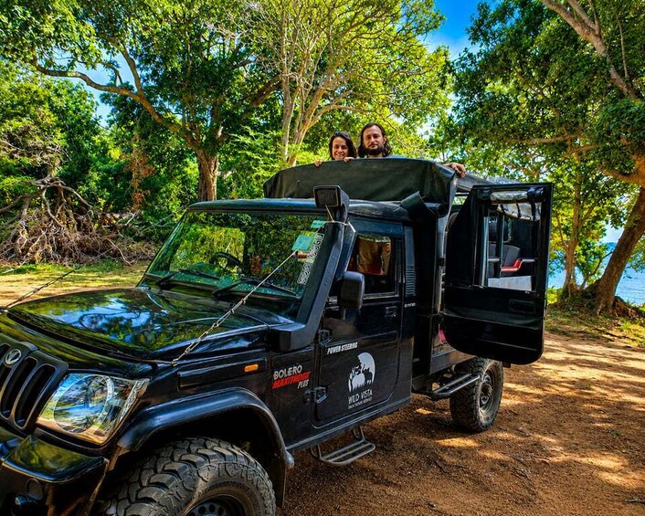 A black off-road vehicle parked on a dirt path surrounded by trees. 4