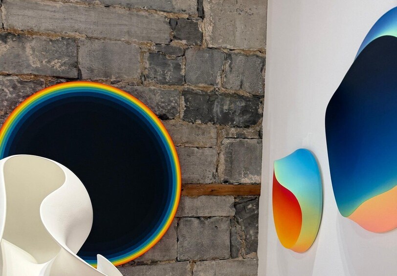A brick wall with a rainbow-colored circular object and abstract wall art. 2
