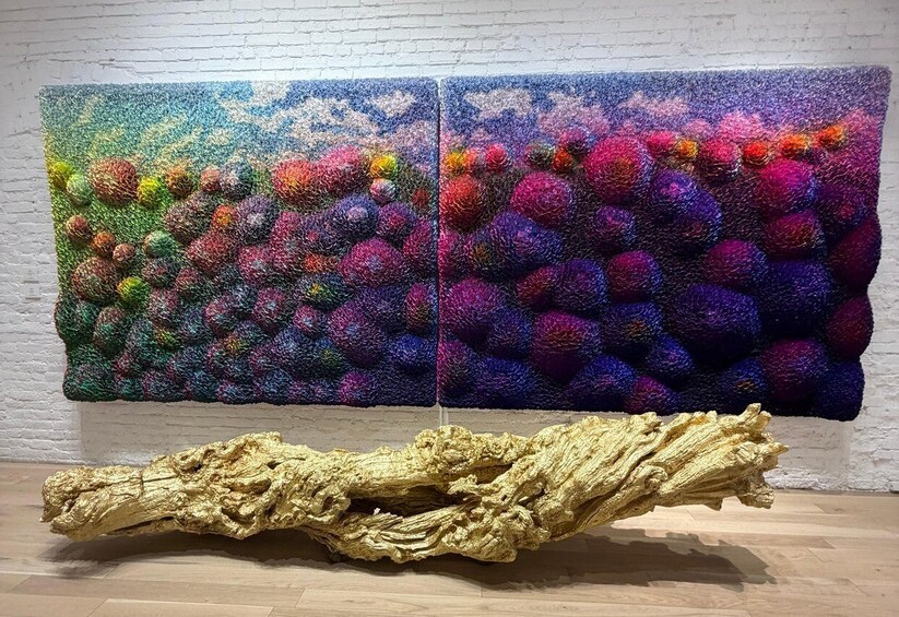 A textured artwork with a golden sculpture in front. 3