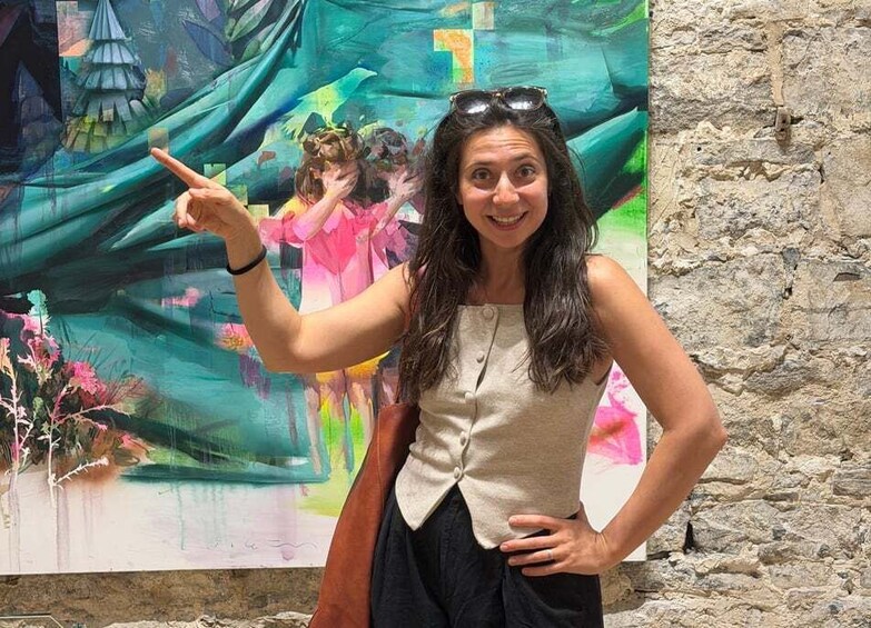 A person pointing at a colorful painting with abstract shapes and figures. 4