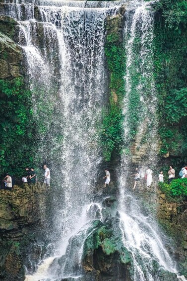 A multi-tiered waterfall surrounded by lush greenery. 1
