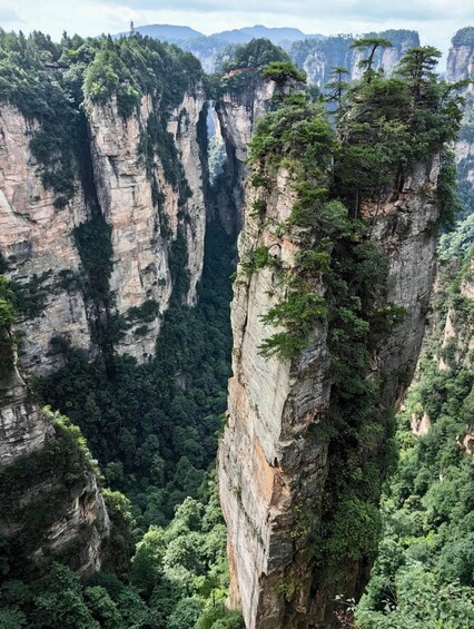 A mountainous landscape with prominent rock formations and dense forestation. 5