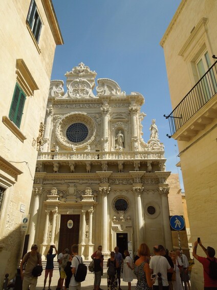 A historic ornate church with intricate carvings and statues, surrounded by tourists. 2