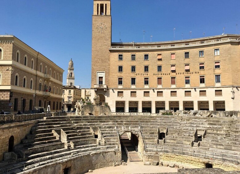 An ancient amphitheater with stone steps and a clock tower in the background. 5