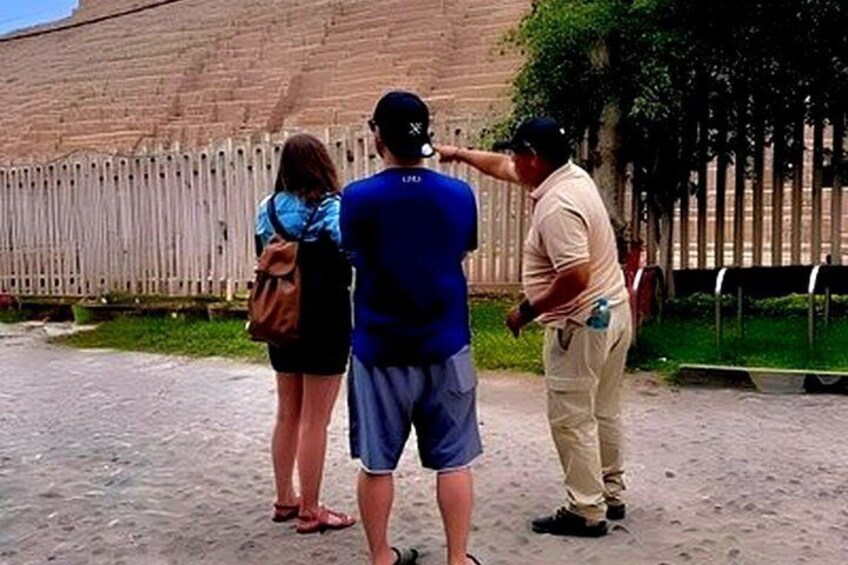 A group of people standing outdoors near a brick wall and a wooden fence. 3