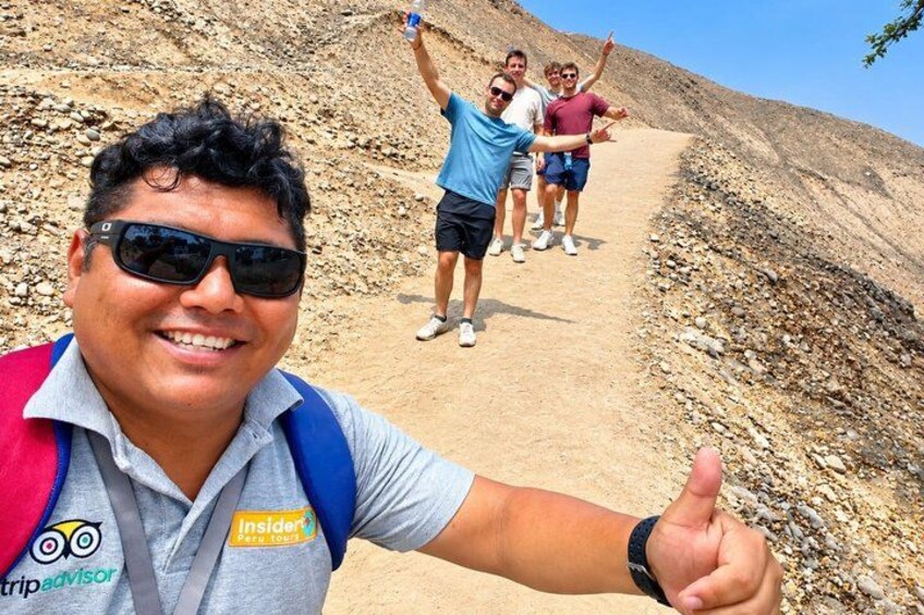 A person giving a thumbs-up gesture, with a rocky path and a group of people in the background. 5