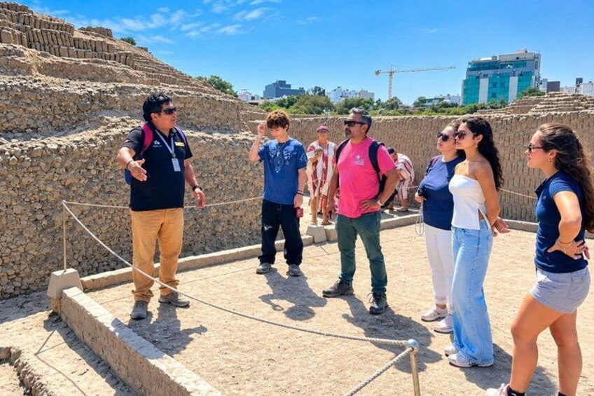 A group of people standing on a stone platform with a rope barrier, overlooking ancient ruins. 3