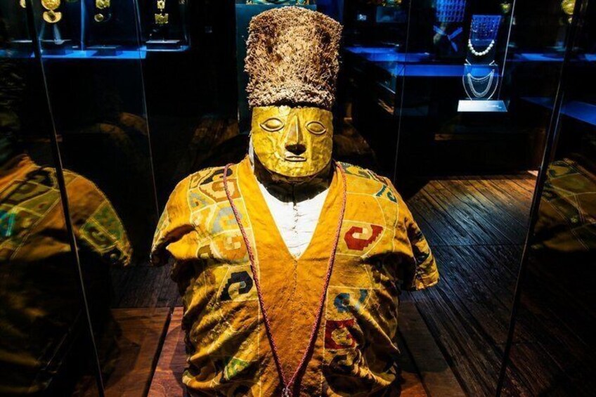 A statue in a museum with intricate patterns and a traditional headdress. 1