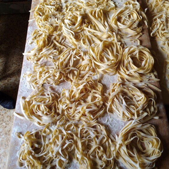 A wooden cutting board with pasta sheets arranged in a circular pattern. 3