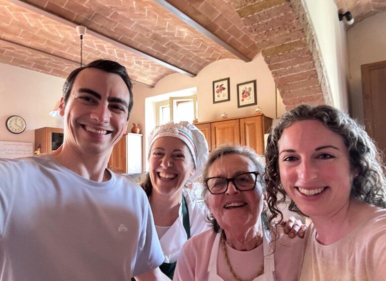 A group of people in a kitchen with brick walls and wooden cabinets. 5