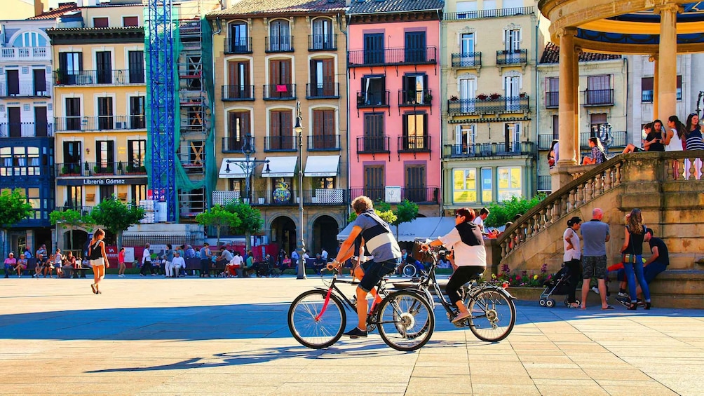 A bustling square with cyclists, pedestrians, and historic buildings. 2