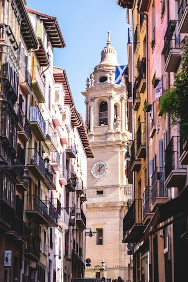 A historic tower with a clock and a flag, surrounded by colorful buildings. 4