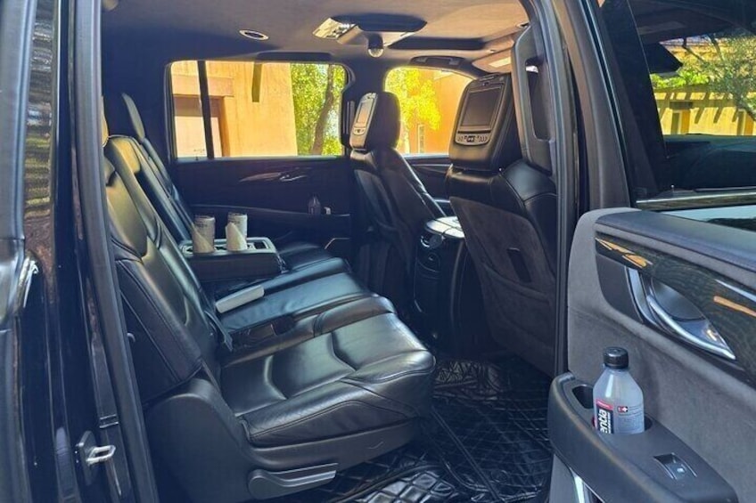 A vehicle interior with black leather seats, a cup holder, and a bottle of water. 2