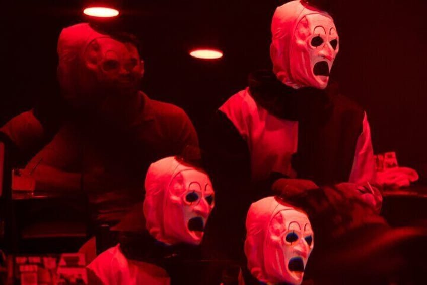 A group of people in red costumes with masks, in a dimly lit room. 4